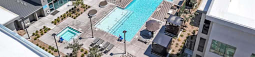 A large swimming pool is surrounded by lounge chairs and umbrellas.