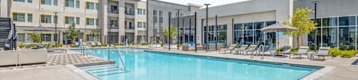 A large swimming pool in front of a building with a clear blue sky above.