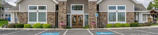 Apartments for Rent in Spokane - Deer Creek - Building Exterior of Clubhouse with Lush Landscaping and View of Parking Lot