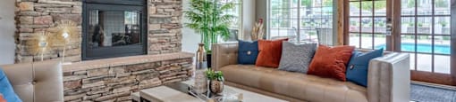 Apartments for Rent in Spokane, WA - Deer Creek - Clubhouse with Leather Sofas, Coffee Table, Fireplace, Glass-Paned Double Doors, and Large Windows.