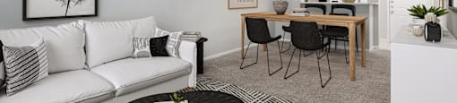 Living room with plush carpet next to the dining area at Sagewood at Westchase apartments in Houston, Texas.