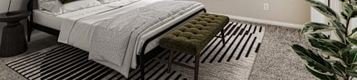 Bedroom with plush carpeting and a large window at Sagewood at Westchase apartments in Houston, Texas.