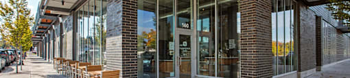 A building with a glass facade and a row of wooden chairs outside.