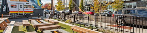 A sunny day at an outdoor seating area with wooden benches and a food truck in the background.