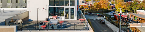 A modern building with a large glass window is surrounded by a parking lot.