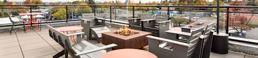 A patio with tables and chairs overlooking a parking lot.