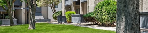 an apartment building with green grass and trees in front of it