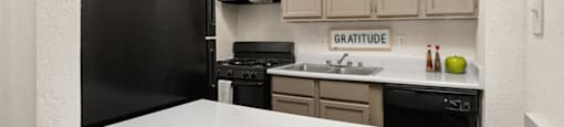 a kitchen with a white counter top and a black refrigerator