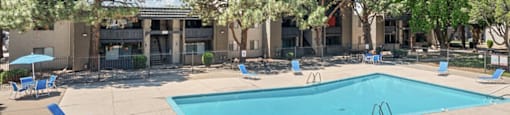 a picture of swimming pool with trees and a blue sky above it