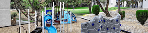 A playground with a blue slide and climbing wall.