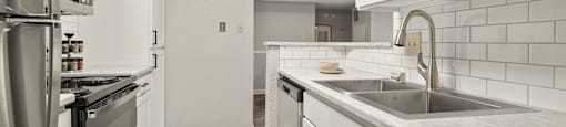 a renovated kitchen with white cabinets and stainless steel appliances