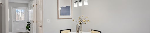 A dining room with a white table and chairs.