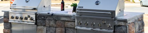 two stainless steel barbecue grills in front of a building