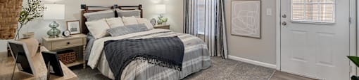 A bedroom with a bed, nightstand, and window.