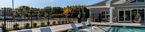 A pool with a metal fence and a building in the background.