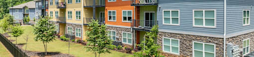 a row of apartment buildings on a hillside with trees