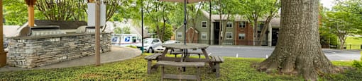 a picnic table with an umbrella next to a tree