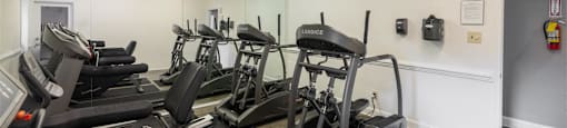 a gym with cardio machines and a ceiling fan