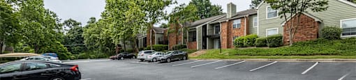 an empty parking lot in front of apartment buildings with cars parked on the street