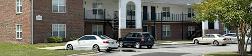 A white car is parked in front of a brick building.