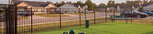 A black metal fence with a green post in front of a grassy area.