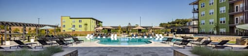 A pool surrounded by wooden deck chairs at Boardwalk at Research Park apartments in Huntsville, AL.