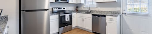 A kitchen with a refrigerator, microwave, oven, and sink.