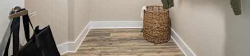 a walk in closet with a white jacket hanging on the wall and a basket on the floor