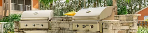 an outdoor kitchen with two grills and two stoves