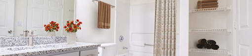 A white bathroom with a toilet, sink, and a shelf.