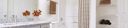 A bathroom with a toilet and a shower with a curtain at Amelia Village apartments in Clayton, NC.