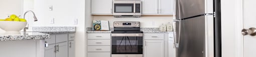 A renovated kitchen with stainless steel appliances and white cabinets at Amelia Village apartments in Clayton, NC.