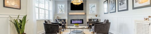 A  room with couches and chairs and a fireplace  in the clubhouse at Amelia Village apartments in Clayton, NC.