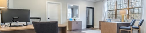 A modern office space with a large desk and chairs in the clubhouse at Amelia Village apartments in Clayton, NC.