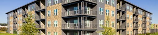 A large apartment building with balconies and multiple windows at Boardwalk at Research Park apartments in Huntsville, AL.
