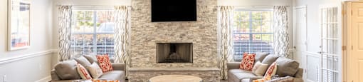 Clubhouse interior at 1322 North Apartments in Auburn, AL, with a fireplace and a flat screen TV mounted above it.