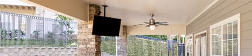 An outdoor patio with a table and chairs and a TV on the wall at 1322 North Apartments in Auburn, AL.
