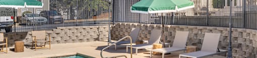 A pool with a stone wall and a fence at 1322 North Apartments in Auburn, AL..