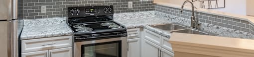 A kitchen with white cabinets and a black stove top oven at 1322 North Apartments in Auburn, AL.