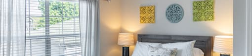 A bedroom with a bed, a ceiling fan, and a window at 1322 North Apartments in Auburn, AL.