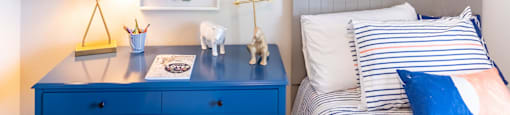 A bedroom with a blue desk and a dinosaur picture on the wall at 1322 North Apartments in Auburn, AL.