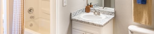 A bathroom with a white toilet, sink, and shower/bathtub at 1322 North Apartments in Auburn, AL.