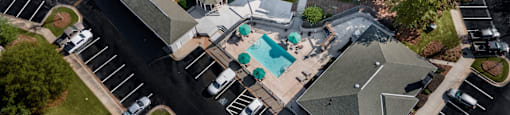 A bird's eye view of a residential area with apartment buildings, a swimming pool, and a parking lot at 1322 North Apartments in Auburn, AL.