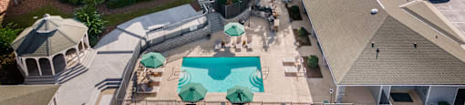 An aerial view of a pool surrounded by a gazebo and apartment buildings at 1322 North Apartments in Auburn, AL.