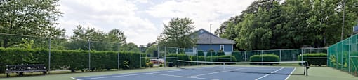 a blue and green tennis court with a bench