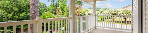 a covered porch with a view of a yard and trees