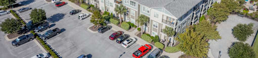 an aerial view of an apartment complex with parking lot and cars