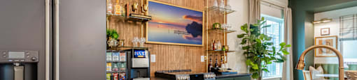 Inside Clubhouse with a Modern Kitchen with Dark Green Cabinets and a Wooden Backsplash.