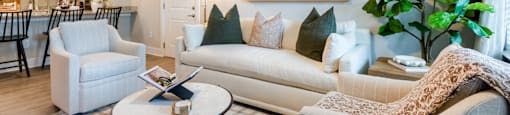 Interior Living Room with a White Couch, Two Sitting Chairs and a Coffee Table.