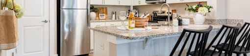 Kitchen Area with a Refrigerator, Microwave and Bar Counter with Chairs.